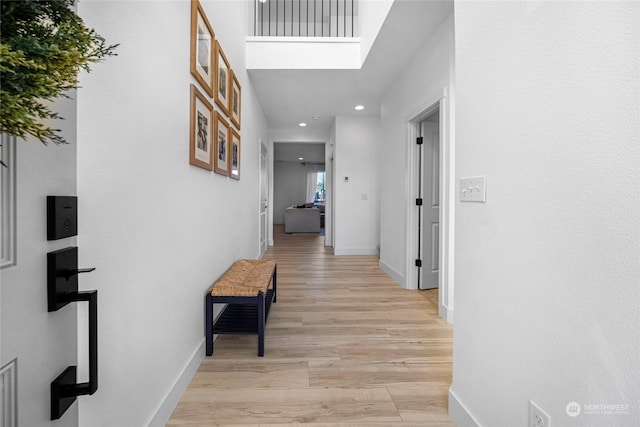 corridor featuring a high ceiling and light hardwood / wood-style flooring