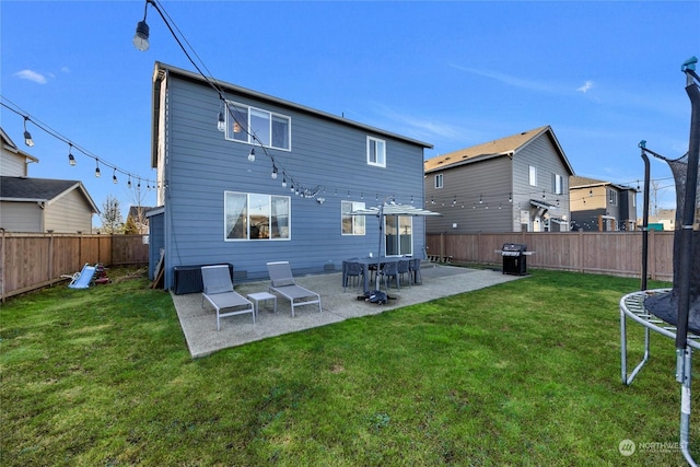 back of house with a patio area, a yard, and a trampoline