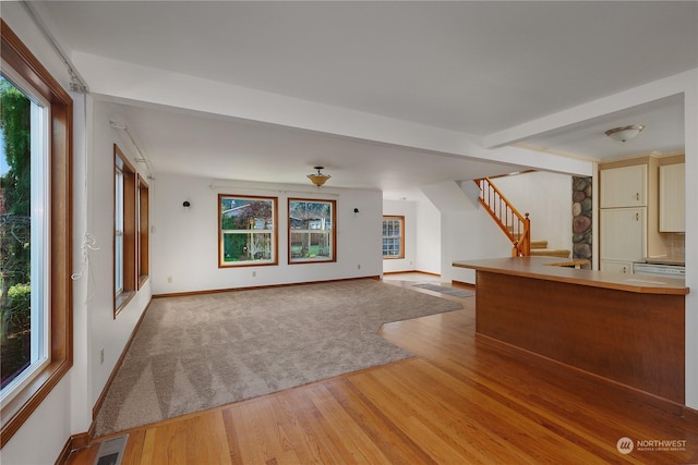 unfurnished living room featuring hardwood / wood-style floors and beam ceiling