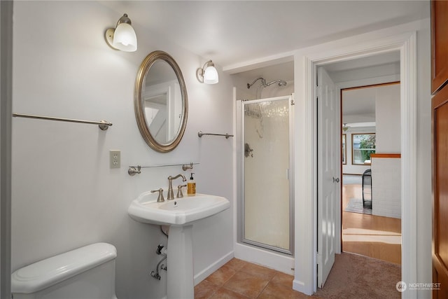 bathroom featuring a shower with shower door, tile patterned flooring, and toilet