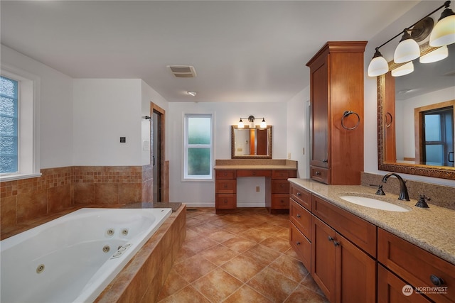 bathroom with a healthy amount of sunlight, tiled bath, and vanity