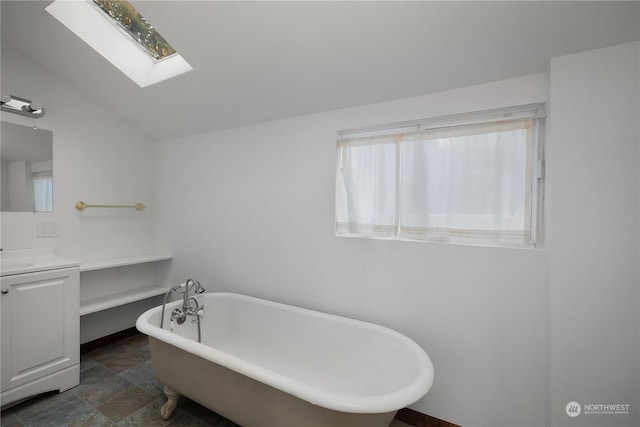 bathroom featuring vanity, a washtub, and lofted ceiling with skylight