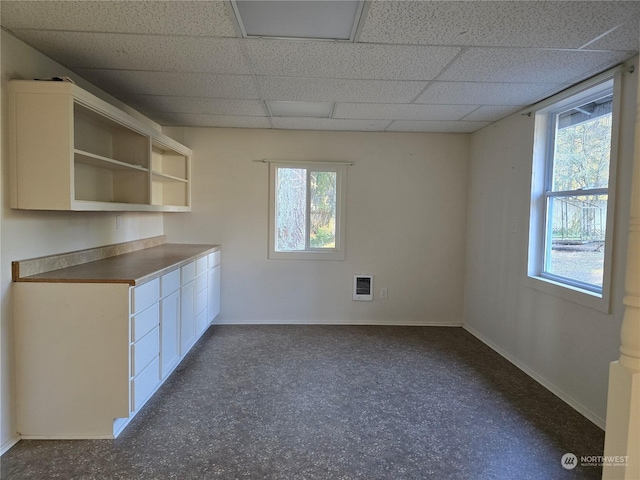 kitchen with heating unit, white cabinetry, a healthy amount of sunlight, and a paneled ceiling