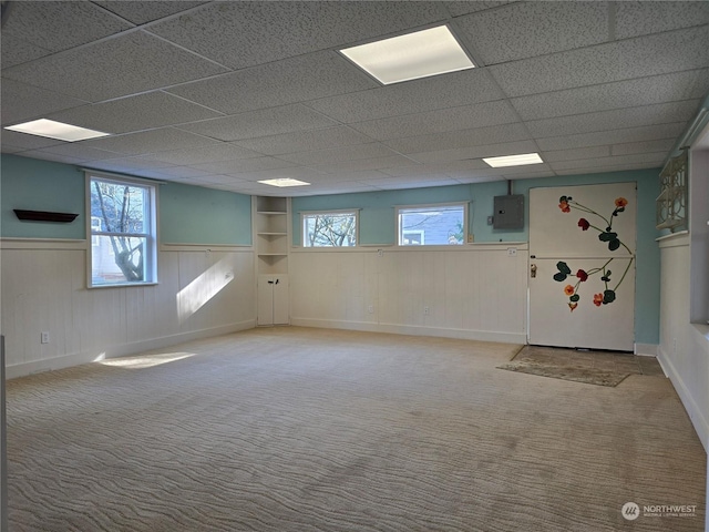 basement with light carpet, electric panel, and a paneled ceiling