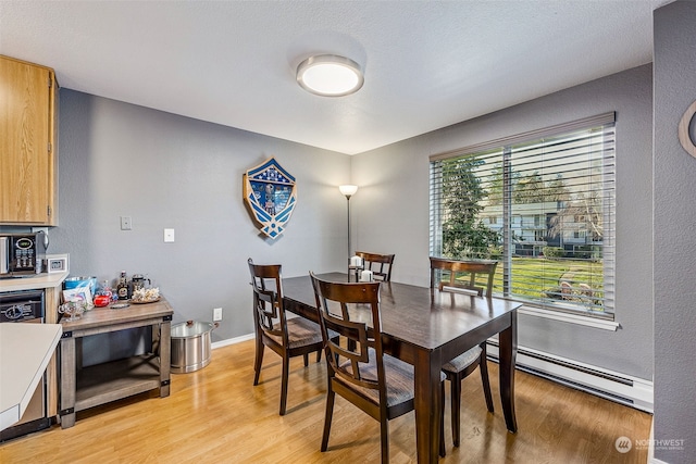 dining space featuring a baseboard radiator and light wood-type flooring