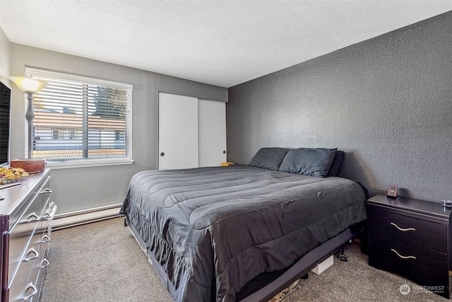 bedroom with a baseboard heating unit, light colored carpet, and a textured ceiling