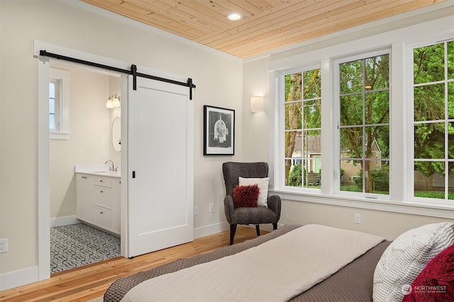 bedroom featuring ensuite bath, sink, wooden ceiling, light hardwood / wood-style flooring, and a barn door