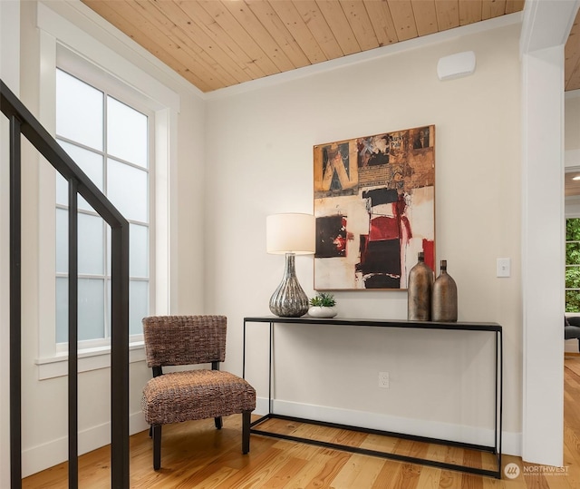 living area featuring wood ceiling, light wood-type flooring, ornamental molding, and plenty of natural light