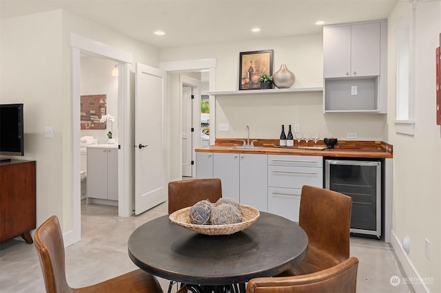 kitchen featuring sink, white cabinetry, beverage cooler, and wooden counters