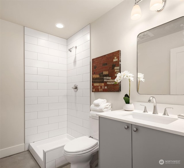 bathroom featuring vanity, toilet, and a tile shower