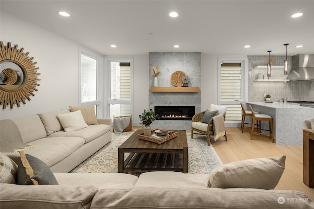 living room with a tile fireplace and light wood-type flooring