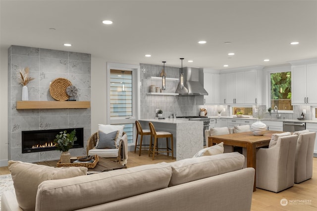 living room with sink, a tile fireplace, and light hardwood / wood-style flooring