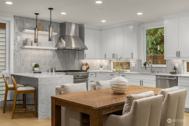 kitchen with exhaust hood, white cabinetry, pendant lighting, and stainless steel appliances