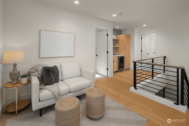 living room with light hardwood / wood-style floors, bar, and wine cooler