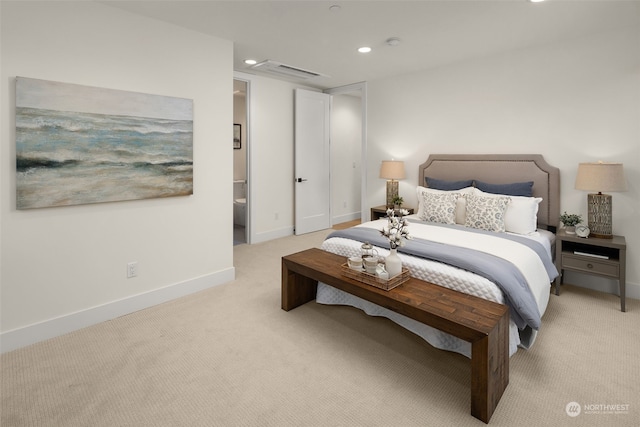 bedroom featuring light colored carpet and ensuite bath