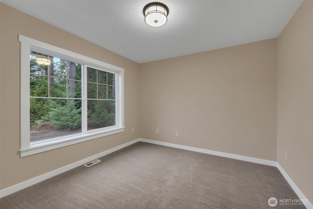 carpeted spare room featuring baseboards, visible vents, and a healthy amount of sunlight