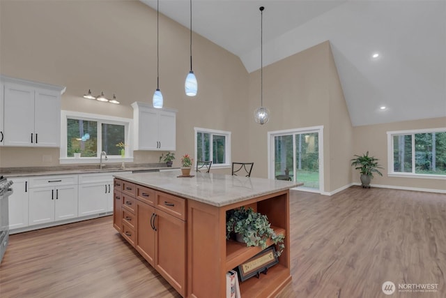 kitchen with a kitchen island, white cabinetry, light stone countertops, open shelves, and brown cabinetry