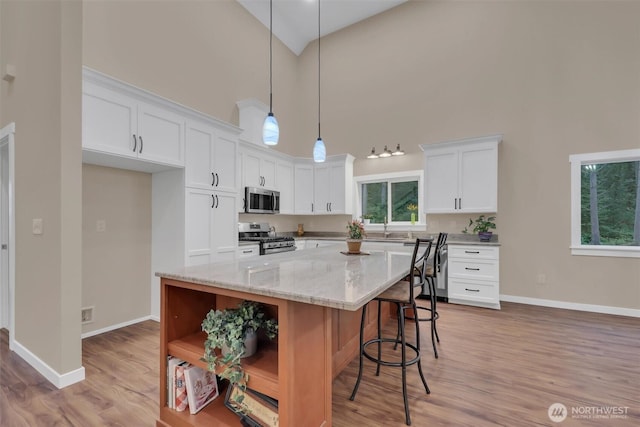 kitchen with stainless steel appliances, white cabinets, hanging light fixtures, a center island, and open shelves