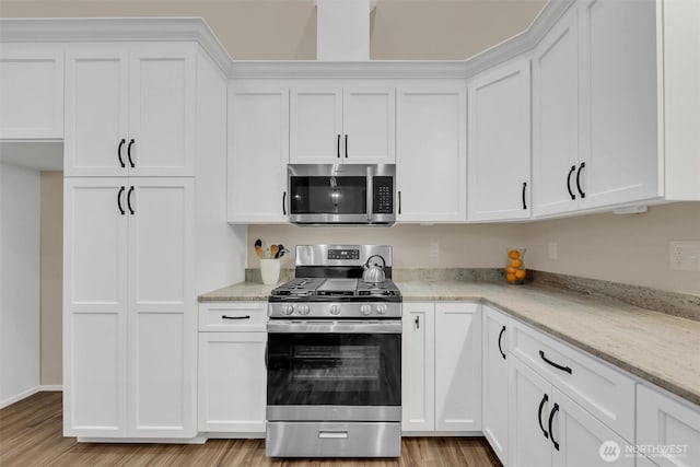 kitchen featuring stainless steel appliances, white cabinetry, and light stone countertops