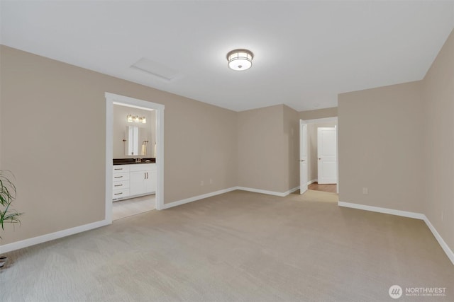 unfurnished bedroom featuring light colored carpet, baseboards, and ensuite bathroom