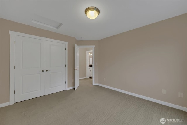 unfurnished bedroom featuring light carpet, attic access, baseboards, and a closet