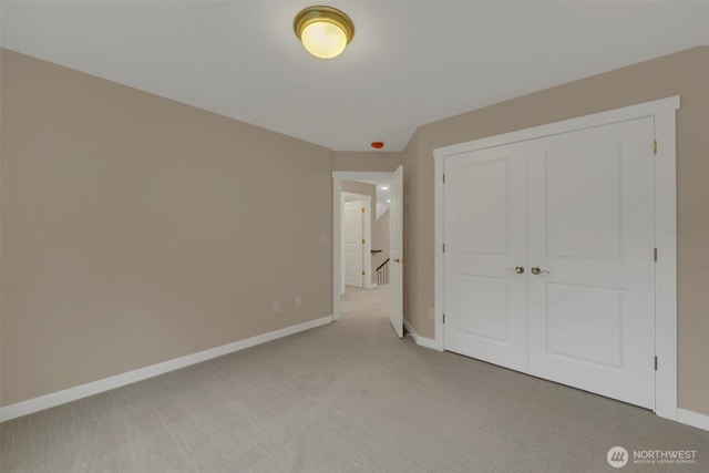 unfurnished bedroom featuring a closet, light colored carpet, and baseboards