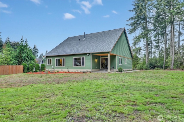 back of property featuring a patio area, a shingled roof, fence, and a yard