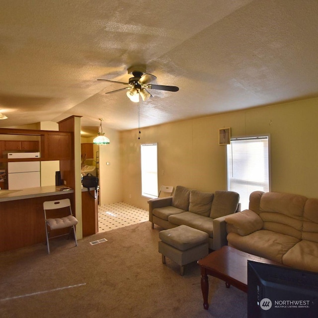 living room with ceiling fan, light colored carpet, and a textured ceiling