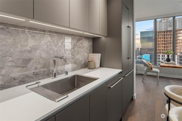 kitchen featuring sink, backsplash, dark hardwood / wood-style flooring, and gray cabinetry