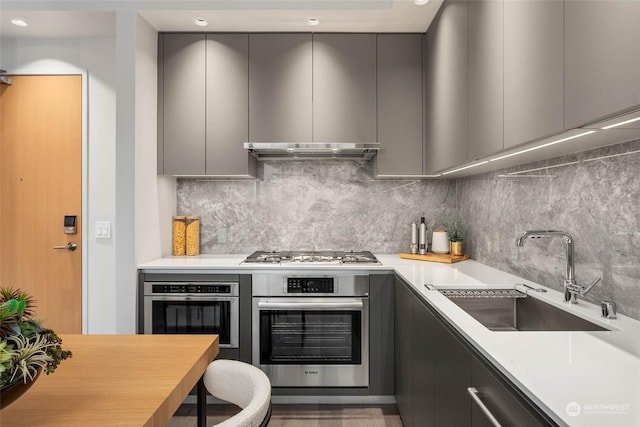 kitchen featuring sink, backsplash, appliances with stainless steel finishes, and gray cabinets