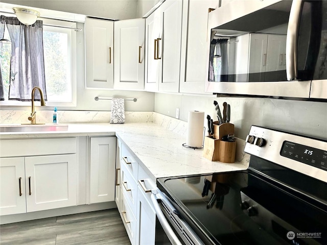 kitchen featuring sink, white cabinets, light stone countertops, and stainless steel appliances