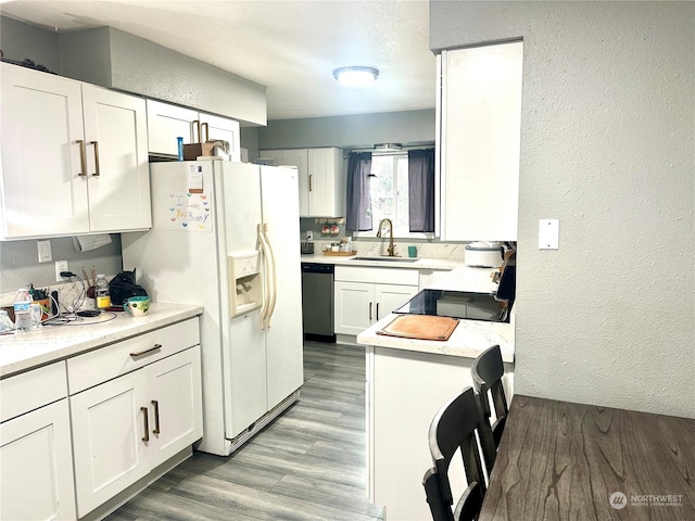 kitchen with white fridge with ice dispenser, white cabinets, range, sink, and stainless steel dishwasher