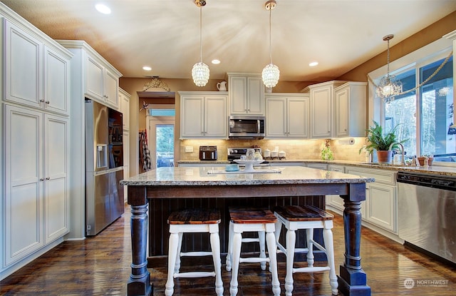 kitchen with sink, decorative light fixtures, a kitchen island, and appliances with stainless steel finishes