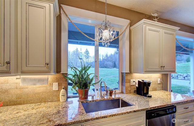 kitchen featuring decorative light fixtures, tasteful backsplash, dishwasher, sink, and light stone counters