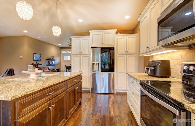 kitchen featuring decorative backsplash, hanging light fixtures, light stone counters, stainless steel appliances, and dark wood-type flooring