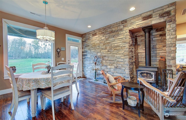 dining space featuring plenty of natural light, dark hardwood / wood-style floors, and a wood stove