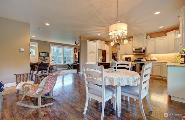 dining space featuring sink, dark hardwood / wood-style floors, and a chandelier