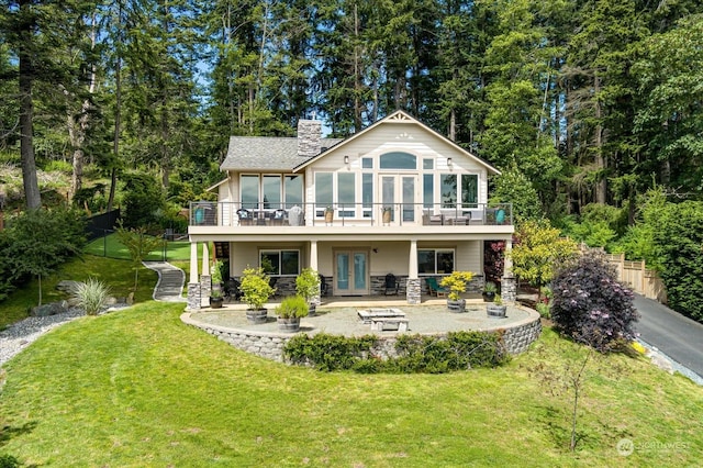 rear view of property featuring a fire pit, a patio area, french doors, and a lawn