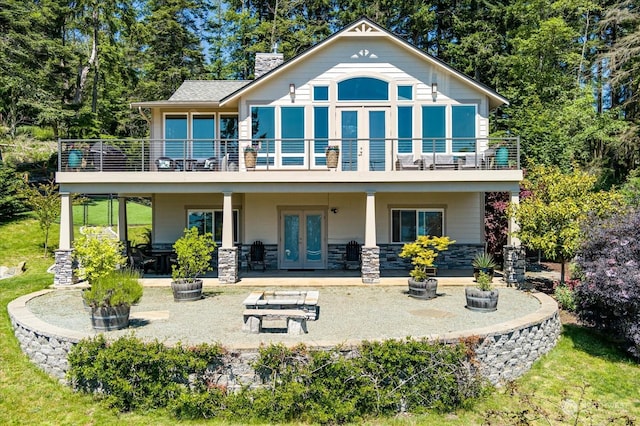 rear view of property with a patio area, french doors, and a balcony