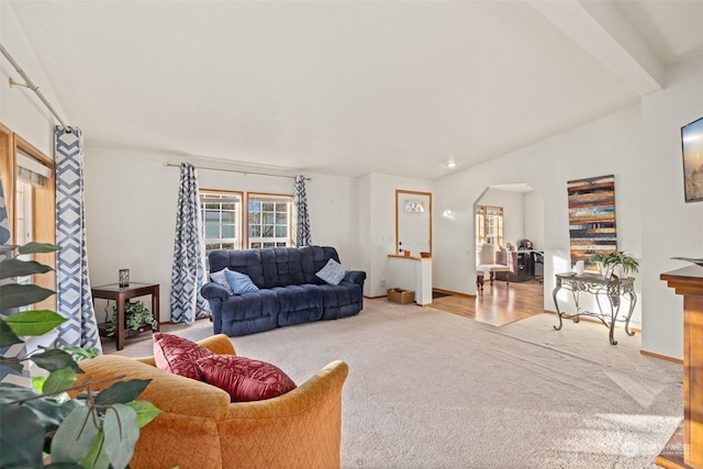 carpeted living room with beam ceiling