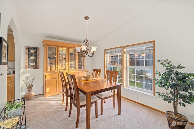 dining room featuring a chandelier, light carpet, and lofted ceiling