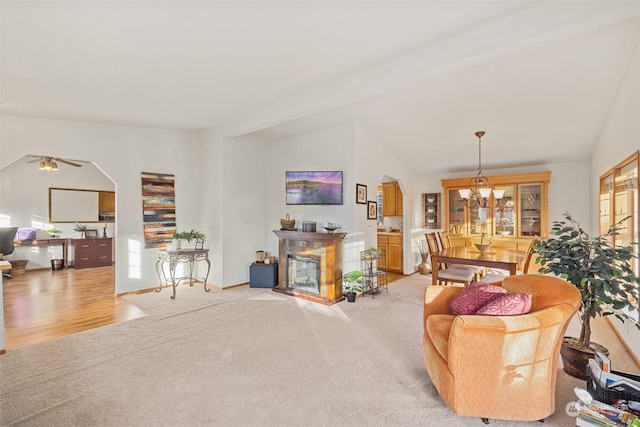 carpeted living room featuring ceiling fan with notable chandelier and beamed ceiling