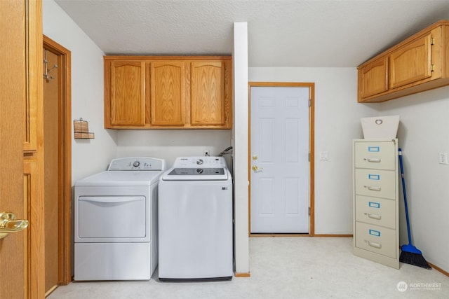 laundry room with cabinets, a textured ceiling, and washing machine and dryer