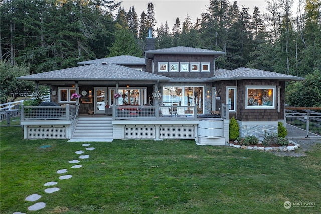 rear view of property featuring a yard, roof with shingles, and fence