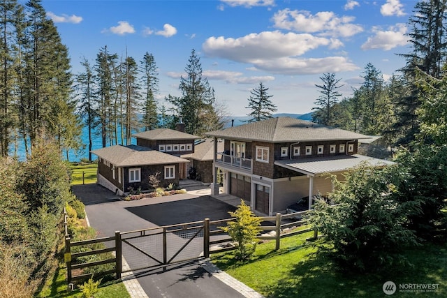 prairie-style home with an attached garage, a fenced front yard, a balcony, driveway, and a gate