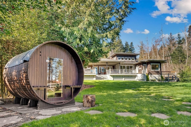 back of property with a chimney, an outdoor structure, and a yard