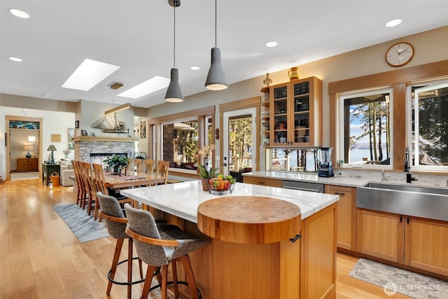 kitchen featuring a kitchen island, light wood-type flooring, a fireplace, a skylight, and a sink