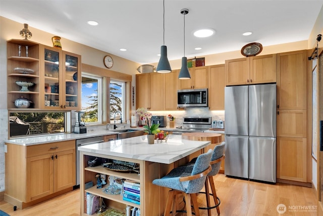 kitchen with open shelves, a sink, a kitchen island, light wood-style floors, and appliances with stainless steel finishes