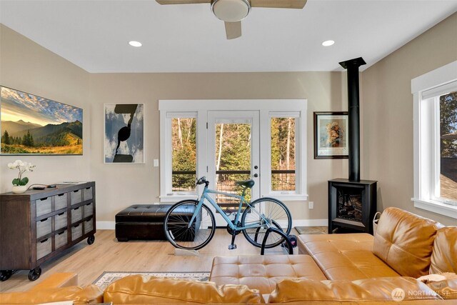 living area featuring a wood stove, recessed lighting, wood finished floors, and baseboards