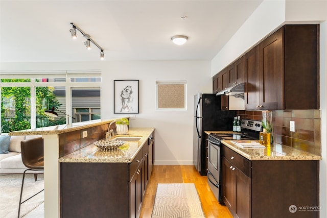 kitchen featuring stainless steel appliances, tasteful backsplash, a kitchen breakfast bar, sink, and light stone counters